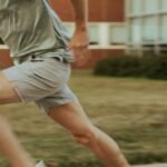 a man in shorts and a t - shirt is playing with a frisbee